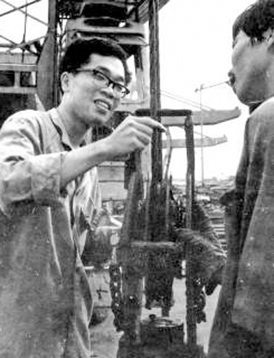 包起帆(左)在上海港碼頭和工友一道研究裝卸貨物工作中存在的問(wèn)題(資料照片)。新華社發(fā)
